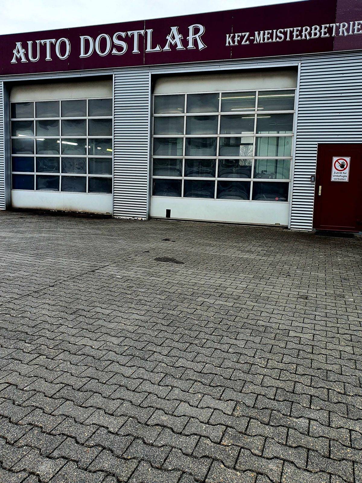Werkstatthalle von Auto Dostlar mit Schild KFZ-Meisterbetrieb und zwei Rolltoren