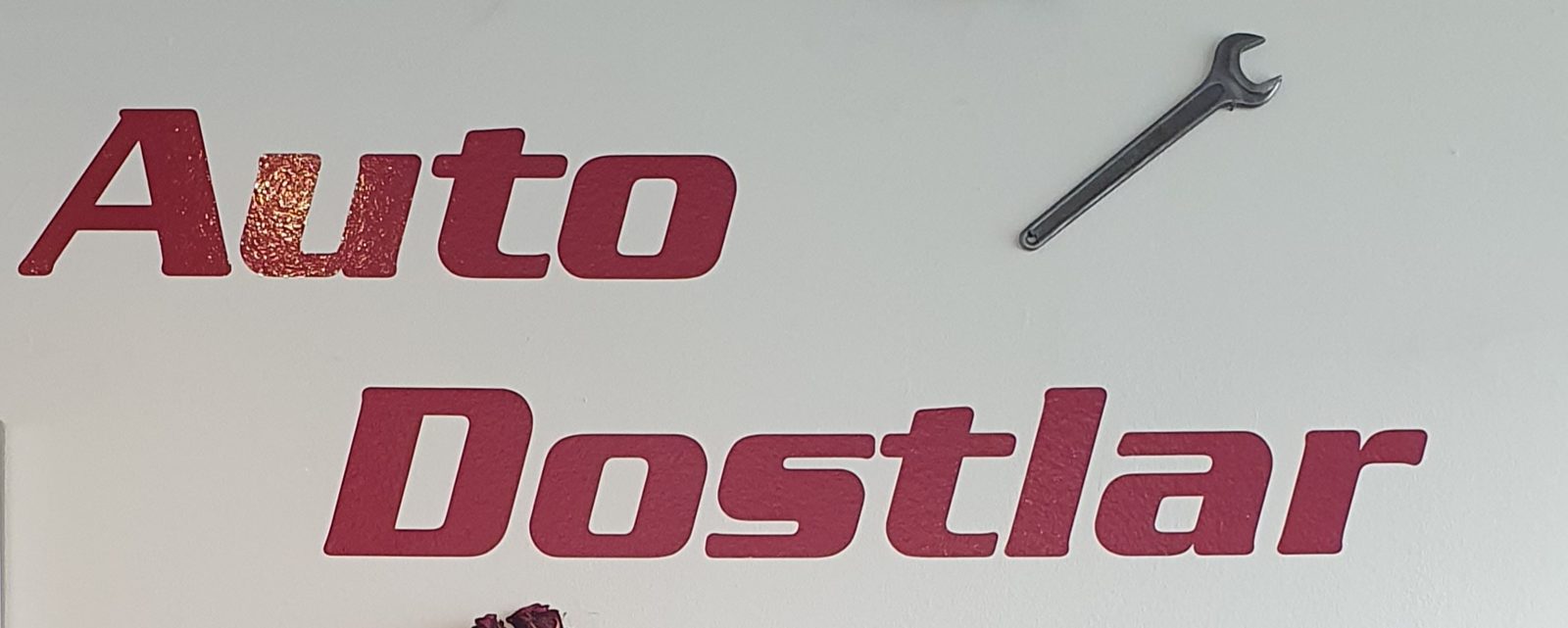Schriftzug Auto Dostlar mit Schraubenschlüssel an der Wand des Kundenraums